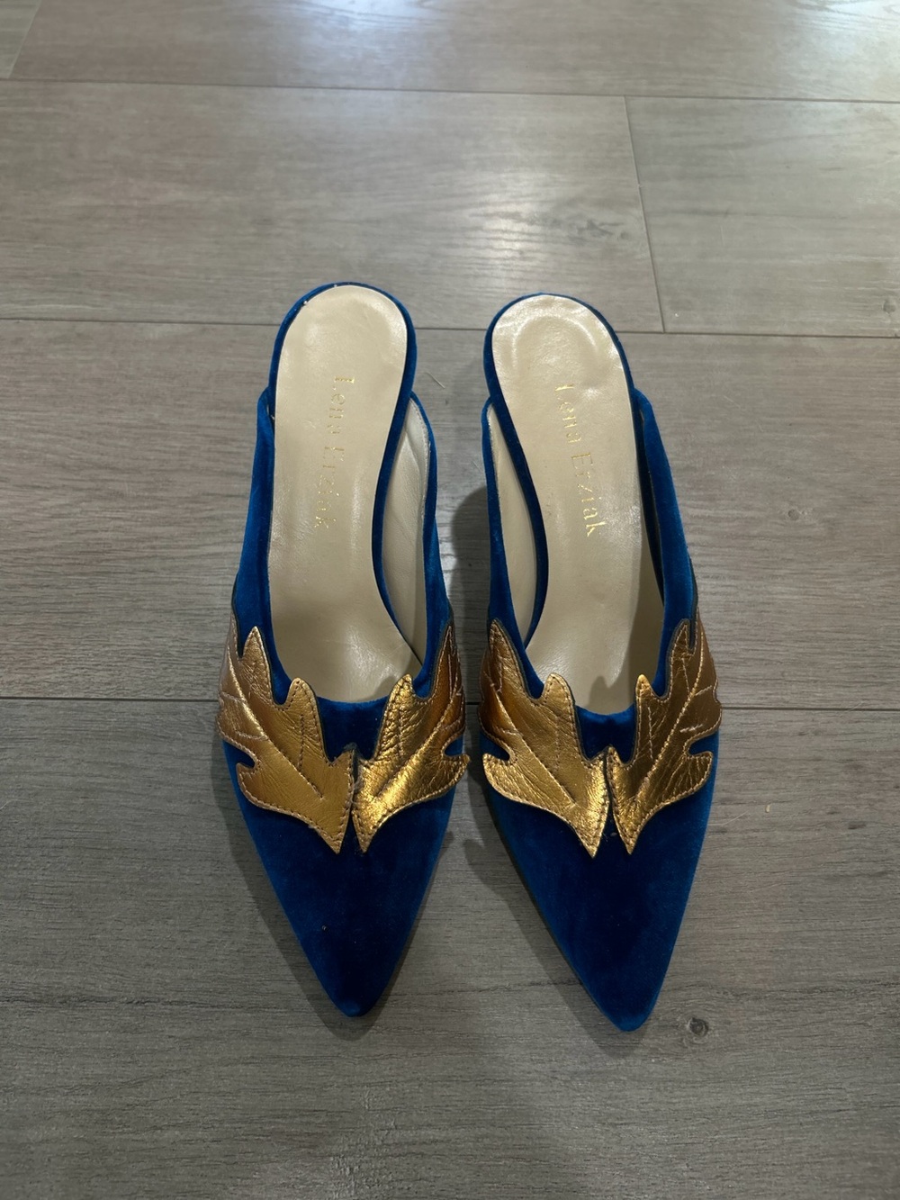 Lena Erziak
Size: EU 39
Blue Suede Pointed Mules with Gold Leaf Accent - Women's